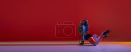 Téléchargez les photos : Portrait of young flexible girl dancing heels dance over red background in neon light. Banner, flyer. Concept of dance lifestyle, modern style, contemporary dance, youth culture, self-expression - en image libre de droit