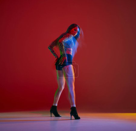 Foto de Contemp. Portrait of young girl dancing heels dance over red background in neon with mixed light. Concept of dance lifestyle, modern style, contemporary dance, youth culture, self-expression - Imagen libre de derechos