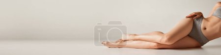 Téléchargez les photos : Cropped image of slim smooth female legs on grey background. Depilation, epilation, laser hair removal. Concept of body and skin care, fitness, natural beauty, health Banner, flyer. Copy space for ad - en image libre de droit