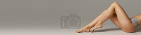 Téléchargez les photos : Cropped image of slim smooth female legs over grey background. Depilation, epilation, laser hair removal. Model in underwear. Concept of body care, fitness, wellness. Banner, flyer. Copy space for ad - en image libre de droit