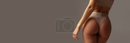 Téléchargez les photos : Cropped image of female buttocks in underwear on grey background. Anti-cellulite care. Fit body shape. Concept of body and skin care, fitness, natural beauty, health. Banner, flyer. Copy space for ad - en image libre de droit