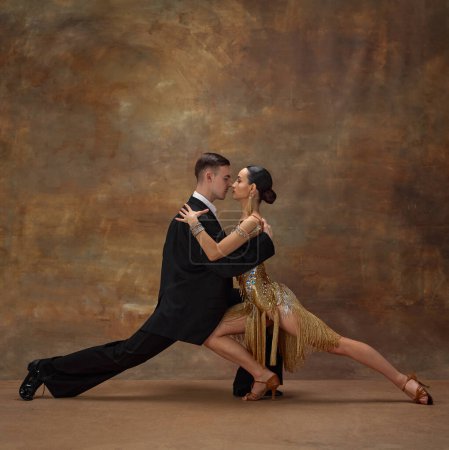Foto de Romance and passion. Man and woman, professional tango dancers in stylish, beautiful stage costumes performing over dark vintage background. Concept of hobby, lifestyle, action, motion. - Imagen libre de derechos