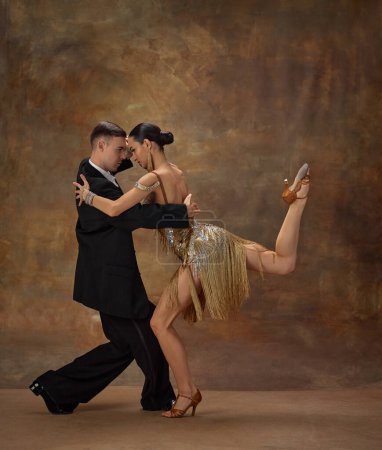 Photo for Man and woman, professional tango dancers in stylish, beautiful stage costumes performing over dark vintage background. Entertainment. Concept of hobby, lifestyle, action, motion, dance aesthetics - Royalty Free Image