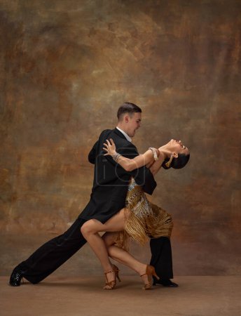 Photo for Man and woman, professional tango dancers in stylish, beautiful stage costumes performing over dark vintage background. Passionate performance. Concept of hobby, lifestyle, motion, dance aesthetics - Royalty Free Image