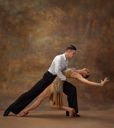 Photo for Man and woman, professional tango dancers in stylish, beautiful stage costumes performing over dark vintage background. Art of movements. Concept of hobby, lifestyle, action, motion, dance aesthetics - Royalty Free Image