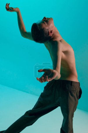 Photo for Contemporary dance style. Young shirtless man dancing contemp, modern dance over blue, cyan studio background. Flexible artist. Concept of art, body aesthetics, motion, action, inspiration. - Royalty Free Image