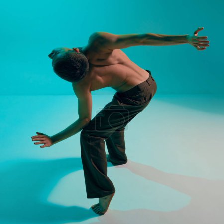 Photo for Contemporary dance style. Young man, professional contemp dancer, performing, dancing over blue, cyan studio background. Modern. Concept of art, body aesthetics, motion, action and inspiration. - Royalty Free Image