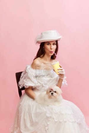 Foto de Coffee to go. Portrait of beautiful lady in vintage dress posing with little dog. Concept of 19th century, fashion, comparison of eras, history, retro. Female model in image of historical character - Imagen libre de derechos
