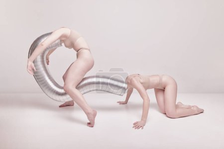 Foto de Abstraction and illusion. Creative photography with two young girls posing in nude underwear over beige studio background. Concept of cringe, queer, art photography, weird people, creativity - Imagen libre de derechos