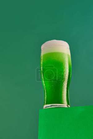 Foto de Bubbles. Glass of foamy frothy green beer over dark green background. Traditional hop taste. Concept of st patricks day celebration, brewery, traditions, alcohol drinks, taste, Irish holiday - Imagen libre de derechos