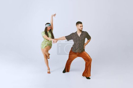 Photo for Couple dance. Artistic talented young man and woman performing disco dance isolated over grey studio background. Retro style. 70s fashion, hobby, creativity, hippie lifestyle, American culture - Royalty Free Image