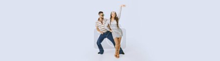 Photo for Young beautiful girl in silver dress and stylish man dancing disco dance isolated over grey studio background. 70s fashion, hobby, hippie lifestyle, American culture. Copy space for ad, text. Banner - Royalty Free Image