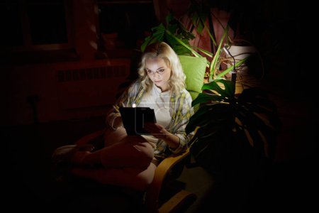 Photo for Battery powered lamp light. Young beautiful woman sitting in dark room with laptop at home in the evening. no electricity, blackout. Freelance, hobby. Concept of power outage. domestic life - Royalty Free Image