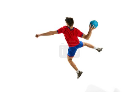 Foto de Vista trasera. Lanzar la pelota en un salto. Hombre joven, jugador de balonmano profesional en uniforme rojo jugando, entrenamiento aislado sobre fondo blanco estudio. Concepto de deporte, acción, movimiento, estilo de vida deportivo - Imagen libre de derechos