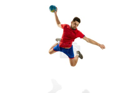 Foto de Salto alto. Hombre, jugador de balonmano profesional en movimiento, lanzando la pelota en un salto aislado sobre fondo blanco del estudio. Concepto de deporte, acción, movimiento, campeonato, estilo de vida deportivo - Imagen libre de derechos