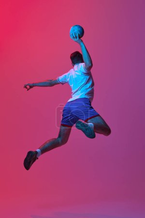 Photo for Back view. Dynamic studio shot of professional male handball player in motion training, playing isolated on gradient pink background in neon light. Concept of sport, action, motion, sportive lifestyle - Royalty Free Image
