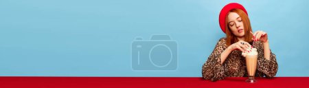 Foto de Young woman in red beret tasting delicious coffee milkshake over blue studio background. Food pop art photography. Complementary colors. Concept of art, beauty, food. Copy space for ad, text. Banner - Imagen libre de derechos
