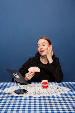 Foto de Beautiful young girl eating sandwich with home made mayonnaise over blue background. Food pop art photography. Complementary colors. Concept of art, beauty, food. Copy space for ad, text. - Imagen libre de derechos
