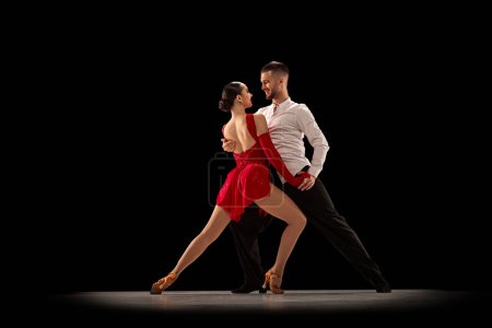 Photo for Beautiful girl and handsome man, professional classical dancers, dancing tango, ballroom over black background. Concept of hobby, lifestyle, action, beauty of movements, emotions, fashion, art - Royalty Free Image
