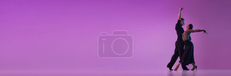 Photo for Man and woman, professional dancers in stylish stage costumes performing tango over purple background on neon lights. Concept of action, beauty of movements, emotions, art. Banner. Copy space for ad - Royalty Free Image