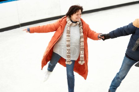 Foto de Happy, smiling woman. Middle-aged couple, having fun outdoors, skating on open air ice rink in winter day. Concept of leisure activity, winter hobby and sport, vacation, fun, relationship, emotions. - Imagen libre de derechos