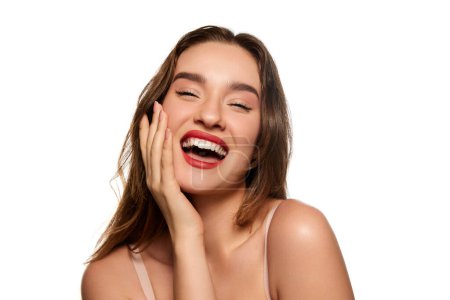 Téléchargez les photos : One beautiful brunette girl with well-kept healthy skin and white perfect teeth smiling, posing against white studio background. Concept of natural beauty, youth, health, wellness, femininity, make-up - en image libre de droit