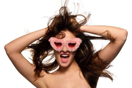 Foto de Happiness. Portrait of young beautiful brunette girl emotionally posing in pink fur glasses over white studio background. Concept of beauty, youth, lifestyle, emotions, cosmetology, fashion, wellness - Imagen libre de derechos