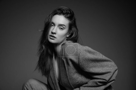 Téléchargez les photos : Black and white photography. Portrait of young beautiful girl with nude makeup posing in stylish oversized jacket. Self-acceptance. Concept of beauty, fashion, youth, femininity, cosmetology - en image libre de droit