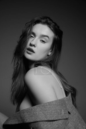 Foto de Black and white photography. Portrait of young beautiful girl with nude makeup posing in stylish oversized jacket. Sensuality and tenderness. Concept of beauty, fashion, youth, femininity, cosmetology - Imagen libre de derechos