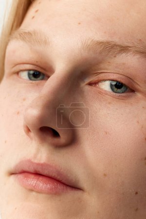 Téléchargez les photos : Portrait en gros plan d'un jeune rouquin aux yeux bleus et au visage clair et bien entretenu. Yeux, nez. Soins de la vue et de la peau. Concept de santé masculine, soins du corps et de la peau, hygiène et cosmétologie masculine - en image libre de droit
