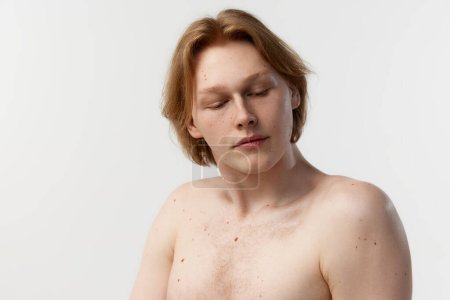 Foto de Natural make beauty. Moles on body. Portrait of young redhead man posing shirtless over grey studio background. Concept of mens health, body and skin care, hygiene and male cosmetology - Imagen libre de derechos