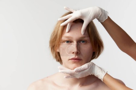 Foto de Young redhead man visiting cosmetologist, taking care after skin with male cosmetics, facial cleansing procedures. Concept of mens health, cosmetology, plastic surgery, body and skin care, medicine - Imagen libre de derechos