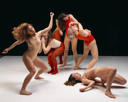 Téléchargez les photos : Esthétique expérimentale de style danse contemporaine. Jeunes filles en body dansant sur scène sur fond noir. Ils se tiennent l'un à côté de l'autre. Concept d'art, jeunesse, mode, flexibilité, inspiration - en image libre de droit