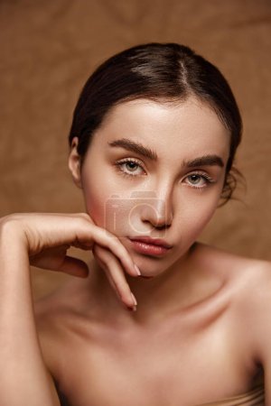 Photo for Purity, innocence. Beautiful young brunette girl with perfect healthy skin posing over brown studio background. Tenderness. Concept of natural beauty, skincare, cosmetology, plastic surgery, health - Royalty Free Image