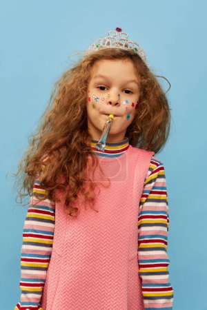 Foto de Birthday girl. Little cute girl, child with curly hair posing in pink dress over blue studio background. Celebration. Concept of childhood, emotions, fun, fashion, lifestyle, facial expression - Imagen libre de derechos