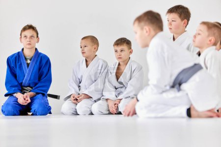 Photo for Group of boys, children in uniform. Judo, jiu-jitsu athletes over grey background. Training activity in sport club. Concept of martial arts, combat sport, sport education, childhood, - Royalty Free Image