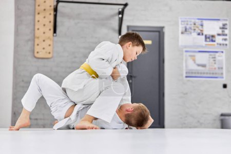 Photo for Future sportsmen. Boys, children in white kimono training, practising judo, jiu-jitsu exercises indoors. Concept of martial arts, combat sport, sport education, childhood, hobby - Royalty Free Image