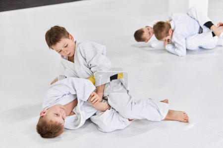 Foto de Boys, children in white kimono training, practising judo, jiu-jitsu exercises indoors. Competition. Strength. Concept of martial arts, combat sport, sport education, childhood, hobby - Imagen libre de derechos