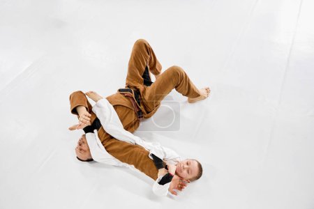 Foto de Top view. Dynamic portrait of man, professional judo, jiu-jitsu coach training with little boy, child in white kimono. Sportive hobby. Concept of martial arts, combat sport, sport education, childhood - Imagen libre de derechos