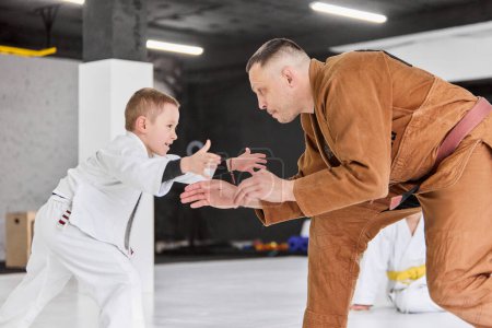 Foto de Dynamic portrait of man, professional judo, jiu-jitsu coach training with little boy, child in white kimono. Sportive occupation. Concept of martial arts, combat sport, sport education, childhood, - Imagen libre de derechos