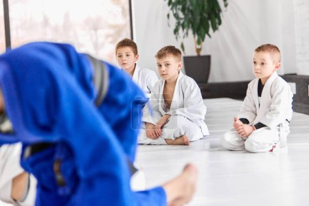 Foto de Boys, children in white kimono attending sport judo, jiu-jitsu class. Learning to fight. Concept of martial arts, combat sport, sport education, childhood, hobby - Imagen libre de derechos