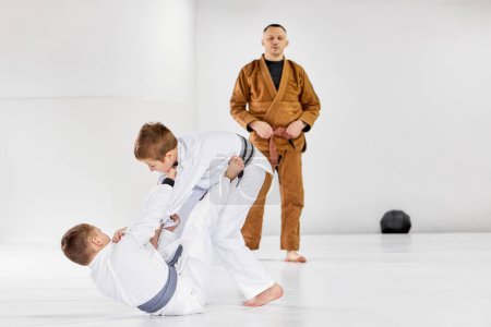 Photo for Coach attentively looking at children. Boys training judo, jiu-jitsu, doing exercises. Sport club for kids. Concept of martial arts, combat sport, sport education, childhood, hobby - Royalty Free Image