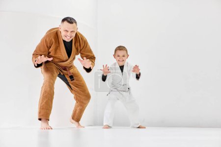 Photo for Coach, professional judo, jiu-jitsu trainer in uniform posing with little boy, child in white kimono. Training activity. Concept of martial arts, combat sport, sport education, childhood, hobby - Royalty Free Image