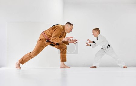 Foto de Retrato dinámico del hombre, judo profesional, entrenamiento de entrenador jiu-jitsu con niño pequeño, niño en kimono blanco. Estilo de vida deportivo. Concepto de artes marciales, deporte de combate, educación deportiva, infancia, - Imagen libre de derechos