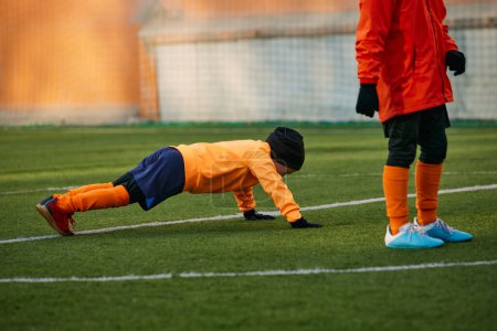 Photo for Little boy, child, football player training with professional coach outdoors on sport field. Doing push up exercises. Concept of sport, childhood, active lifestyle, hobby, sport club - Royalty Free Image