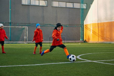 Foto de Position on field. Boy, child, playing football, training on sports field outdoor. Running with ball, dribbling. Concept of sport, childhood, active lifestyle, hobby, sport club - Imagen libre de derechos