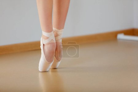 Téléchargez les photos : Image recadrée de jambes féminines debout sur la pointe dans une école de studio de ballet à l'intérieur. Artiste de ballet classique. Couleurs pastel tendres. Concept de ballet classique, danse art, éducation, beauté, chorégraphie - en image libre de droit