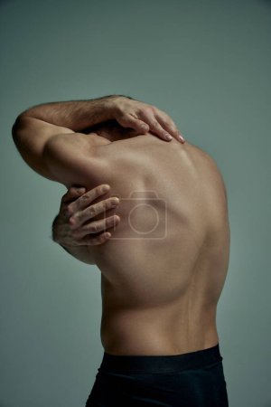 Téléchargez les photos : Round back. Male strong healthy back. Model posing shirtless over pale green studio background. Muscular body shape. Concept of mans beauty, sportive and healthy lifestyle, fashion - en image libre de droit