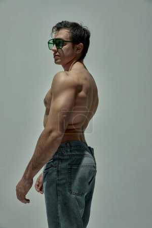 Photo for Relief strong body. Handsome young man with strong muscular body shape posing over grey studio background. Concept of mans beauty, sportive and healthy lifestyle, fashion, strength - Royalty Free Image