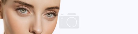 Foto de Cropped image of female face, eyes over grey background. Natural makeup look. Deep look. Vision. Concept of cosmetology, cosmetics, health, natural beauty. Banner, flyer. Copy space for ad - Imagen libre de derechos